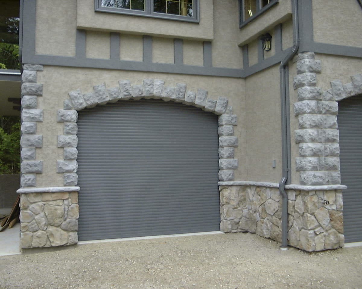 Roll-up garage door fitted inside a stone archway entrance