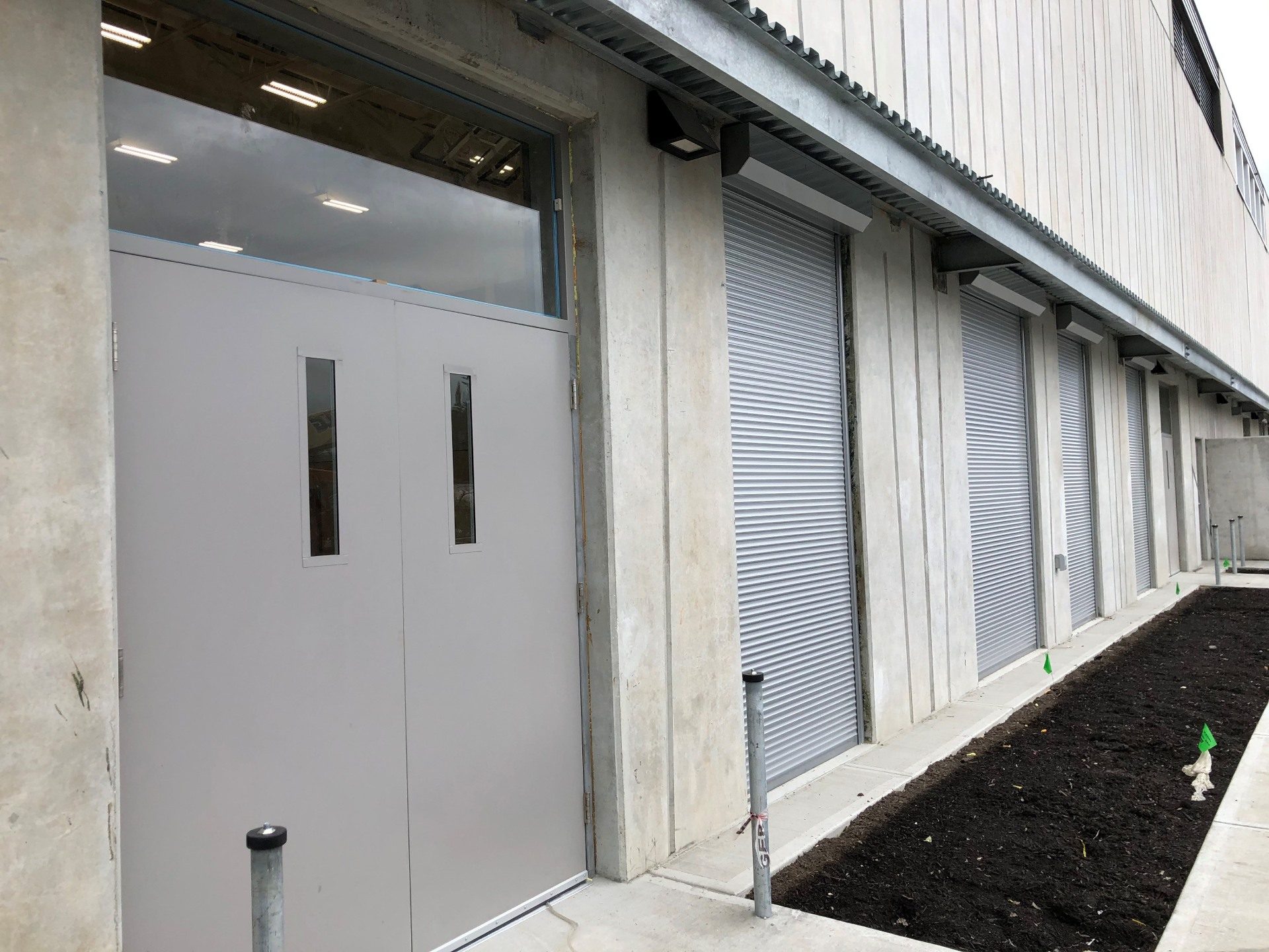 Run of grey roll shutters closed across narrow windows on a concrete institutional building