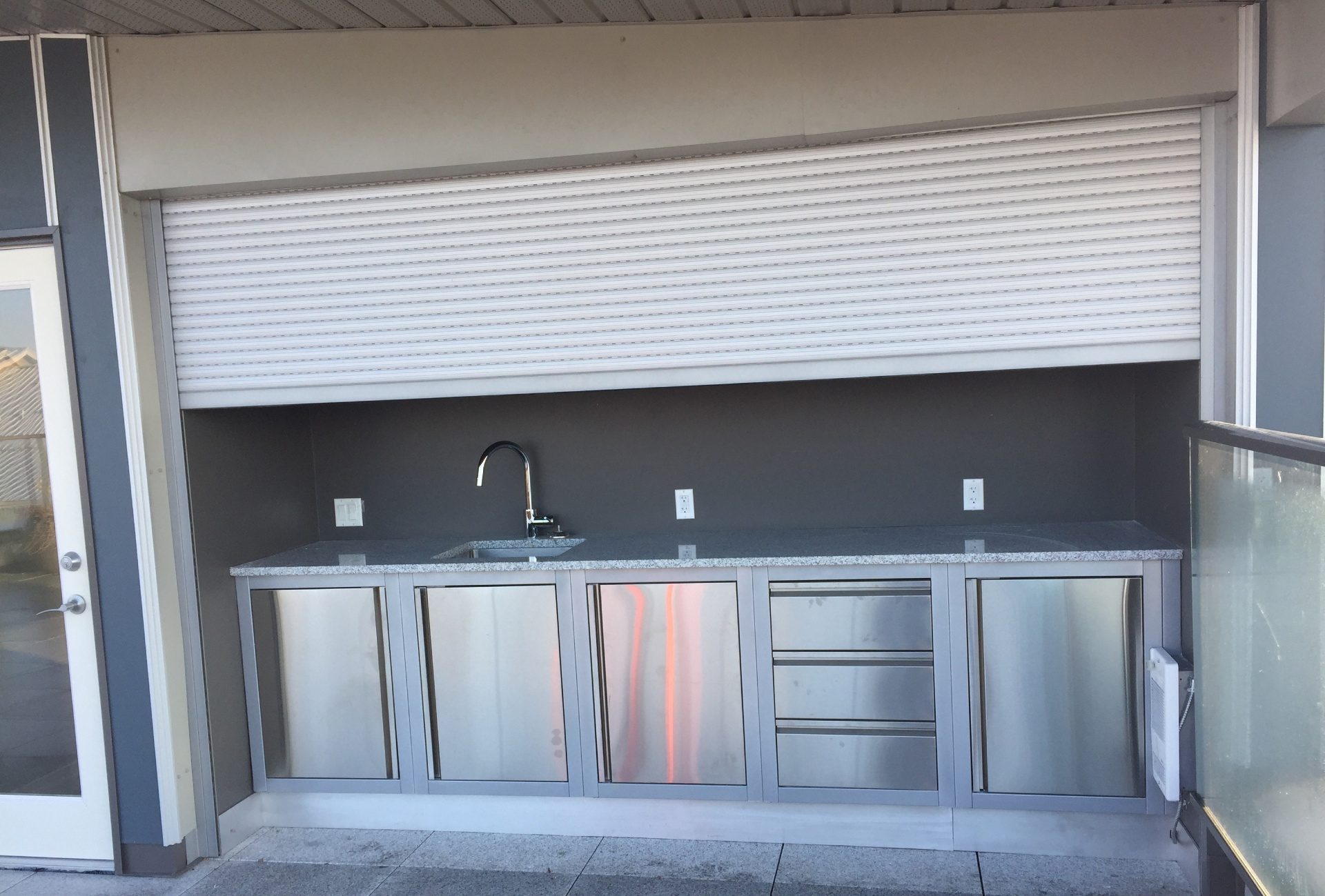 White roll shutter raised above a stainless steel outdoor servery counter