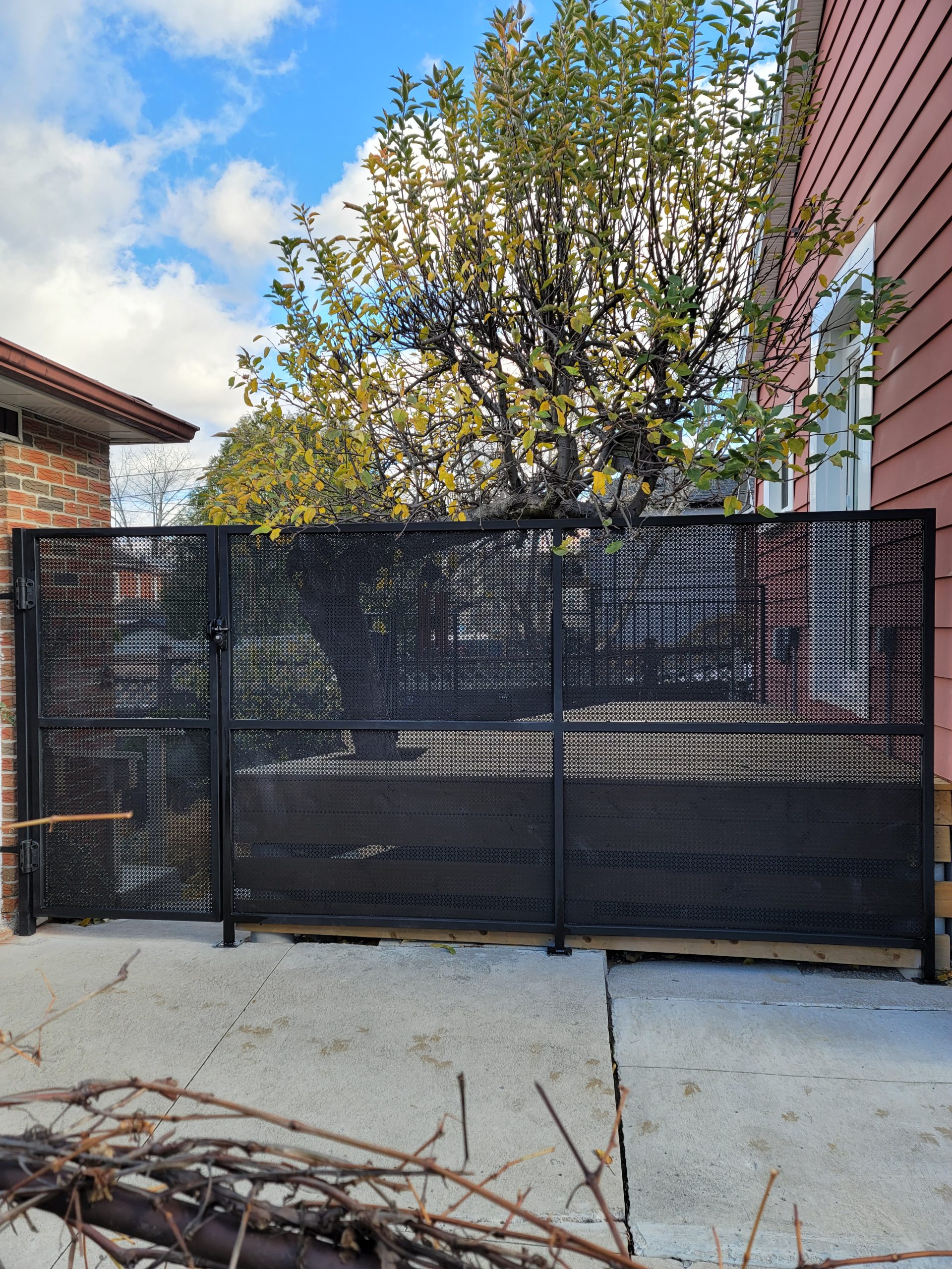 Black metal driveway security gate installed across a residential entry